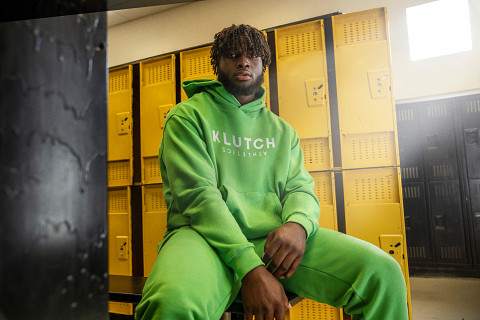 Will Anderson Jr. models a green Klutch sweatsuit in a locker room.